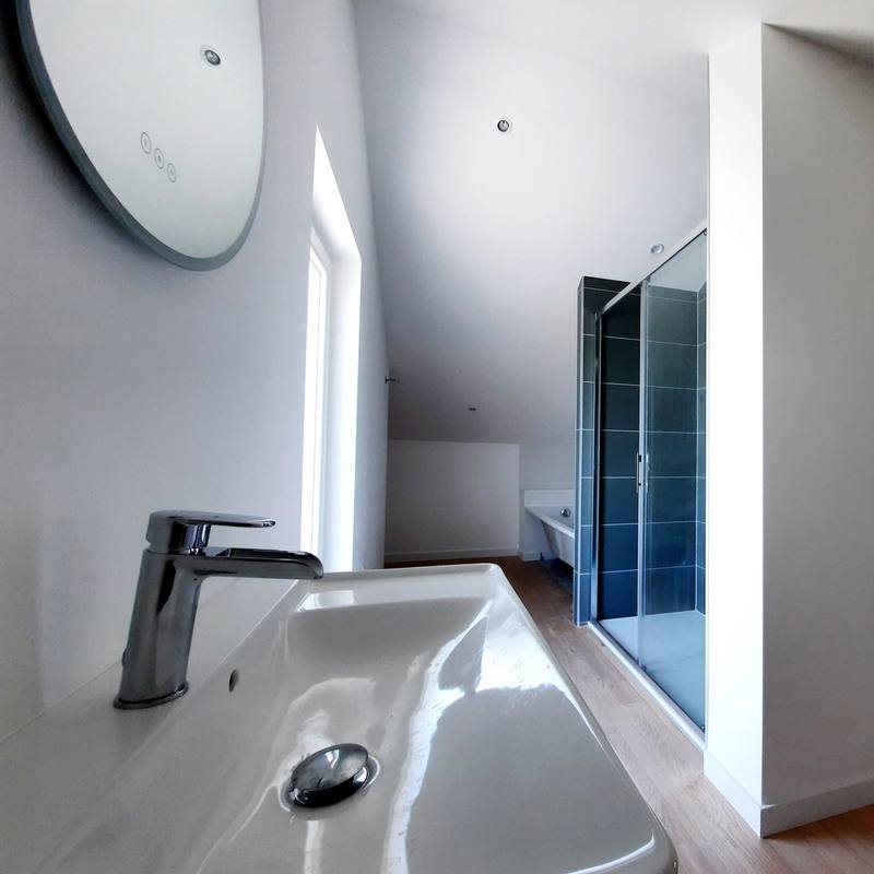 Salle de bain rénovée avec vasque, miroir rond et douche à l’italienne
